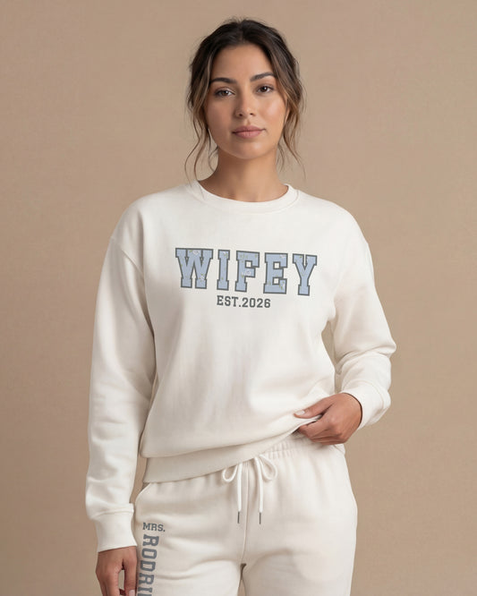 Woman wearing a white sweatshirt with 'WIFEY EST. YEAR' print. Wifey Sweatshirt and Joggers Set
