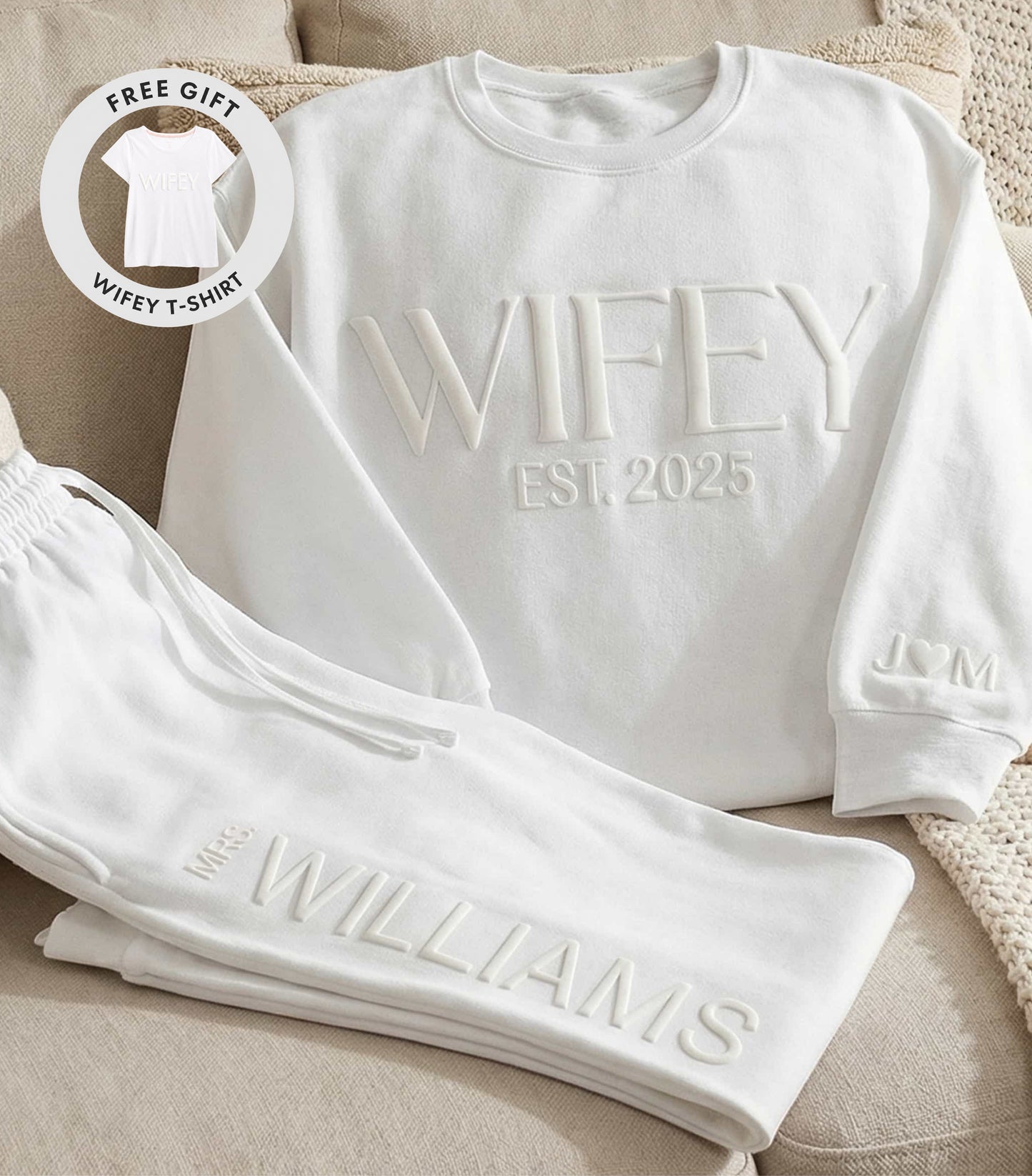 White sweatshirt and pants set with 'WIFEY EST. 2025' text on a beige surface.