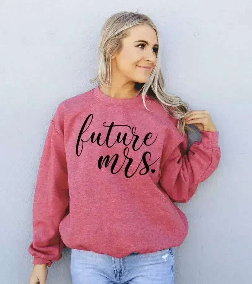 Woman wearing a pink sweatshirt with 'future mrs.' text against a white background