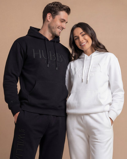Couple wearing matching 'Hubby' and 'Wifey' hoodies and joggers with personalization. Wifey and Hubby hoodie and joggers sets with 3D puff print
