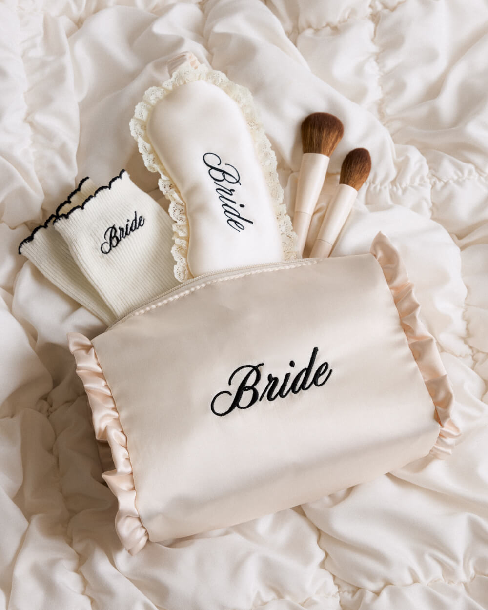 Set of makeup brushes and pouches with 'Bride' embroidery on a textured white surface