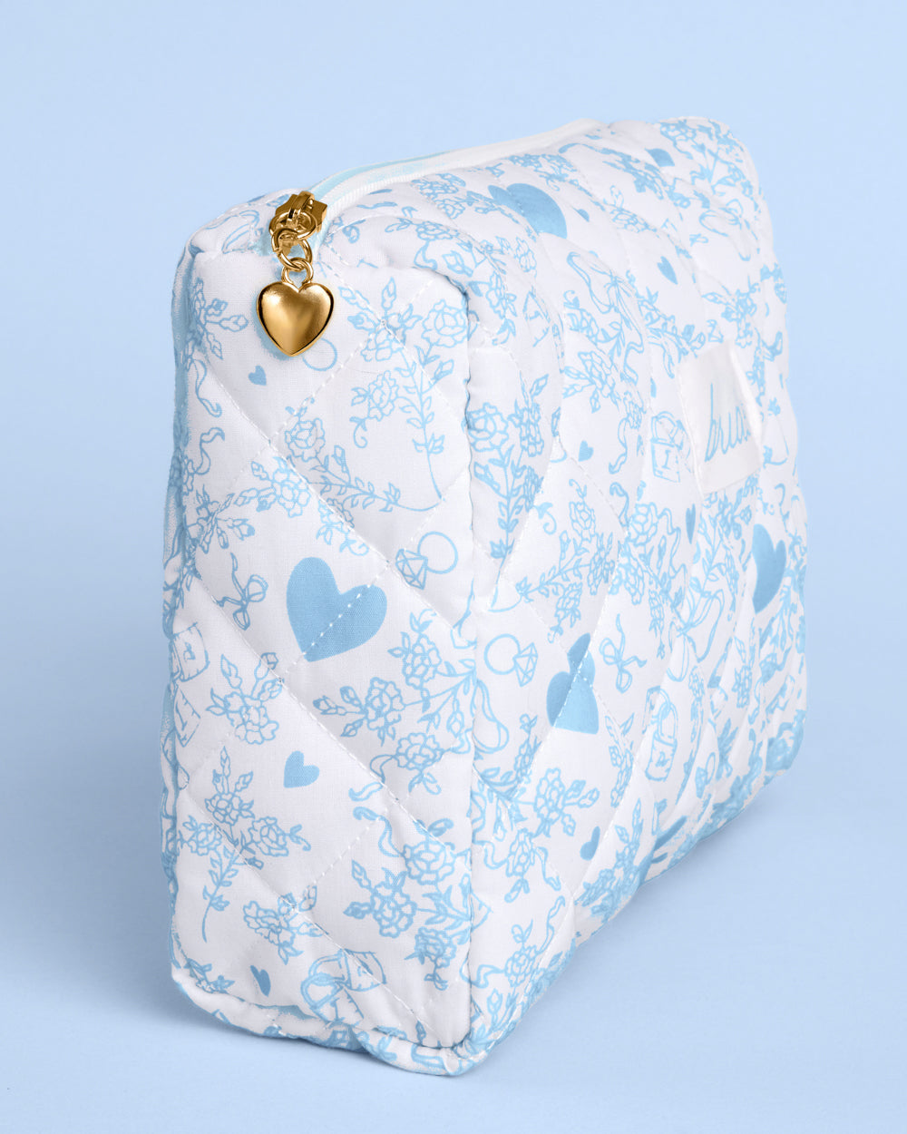 White pouch with blue heart patterns and a gold heart clasp on a light blue background